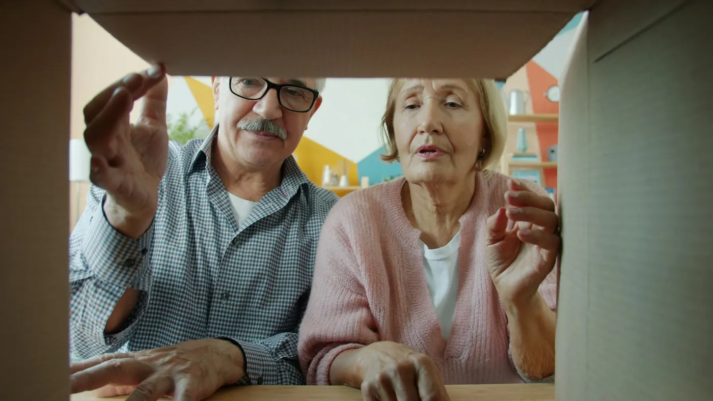 Coppia di anziani che apre una scatola appena consegnata